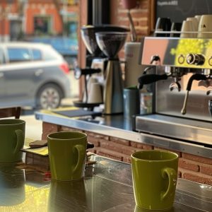 Koffietassen op een toog met een groot industrieel koffiemachine in de achtergrond